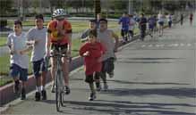 Mark Zaleski/The Press-Enterprise
Ironman competitor Cherie Grunfeld, on her bicycle, and her group of young athletes make their way around East Valley High School in Redlands. She has been helping them reach their goals in swimming, running and bicycling.